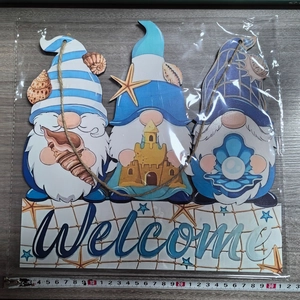 Detail of wooden welcome sign with blue ocean gnomes, starfish and fishing net decor