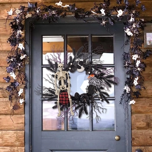 Halloween wreath with skeleton, black pumpkins and Happy Halloween sign on front door