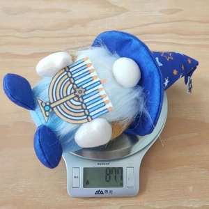 Vue détaillée d'un gnome de Hanoucca bleu tenant une Menorah sur une balance