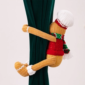 Detail of gingerbread man curtain buckle with knitted texture and red scarf on green fabric