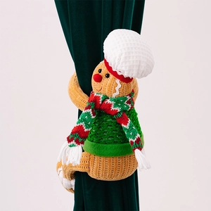 Detail of Christmas gingerbread man curtain buckle with knitted scarf and chef hat decoration