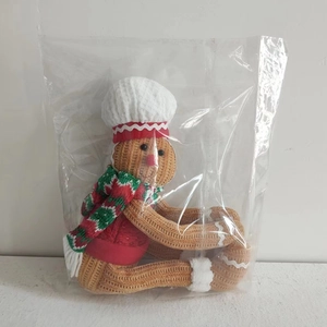 Detail of gingerbread man curtain tie-back with red knit sweater and chef hat