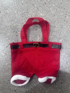 Detail of red Christmas trousers gift bag with white fur trim and black belt buckle