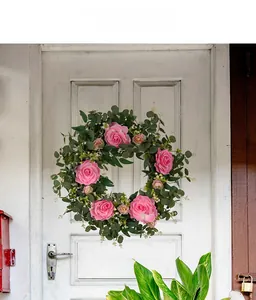 Detail of a pink camellia wreath with eucalyptus leaves on a vintage white door