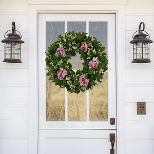 Detailansicht künstlicher rosa Rosen und grüner Blätter an einem Blumen-Türkranz