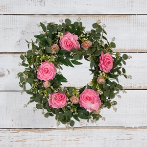 Macro detail of pink camellia flowers and green eucalyptus leaves on wooden background