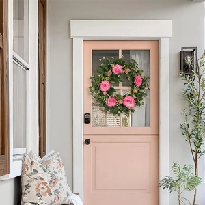 Detail view of a pink camellia wreath with green eucalyptus leaves on a pink door