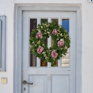 Detail von rosa Kunstrosen und grünen Blättern an einem Frühlingskranz an einer Tür
