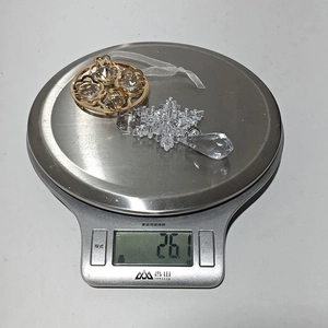 Detailed shot of transparent acrylic snowflake pendant weighing 26.1g on a scale