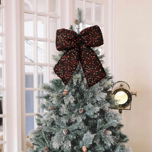Sparkling red sequin bow topper on a snowy Christmas tree for festive home holiday decoration
