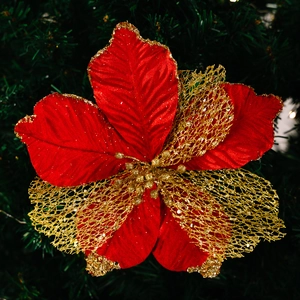 Glittery red and gold poinsettia Christmas flower decoration on a green tree