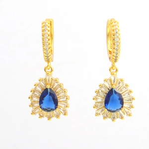 Detail van goudvergulde oorhangers met blauwe peergeslepen stenen en witte zirkonia accenten