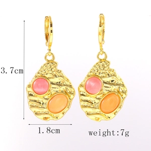 Détail des boucles d'oreilles dorées texturées avec pierres roses, oranges et mesures