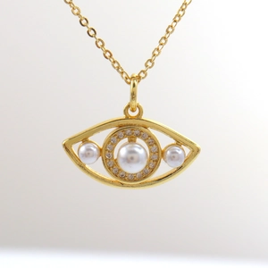 Macro-opname van vergulde evil eye hanger met witte parels en zirkonia voor vrouwen