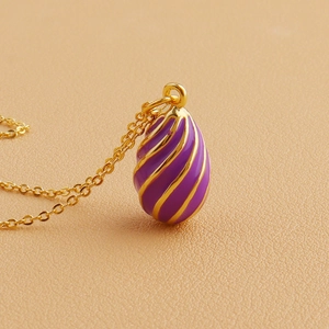 Macro detail of purple enamel egg pendant necklace with gold spiral texture lines