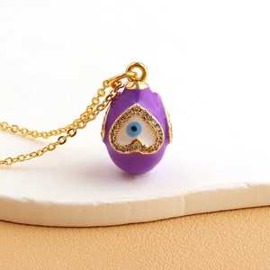 Macro detail of gold-plated purple enamel heart evil eye pendant with sparkling crystals