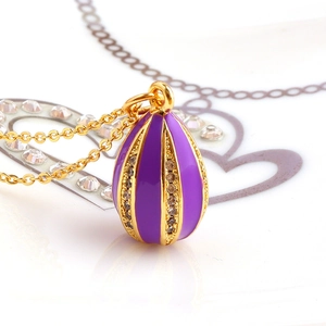 Macro detail of purple enamel easter egg pendant with gold stripes and zircon inlay