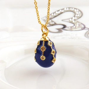 Macro shot of Fabergé style dark blue enamel egg pendant with gold diamond patterns