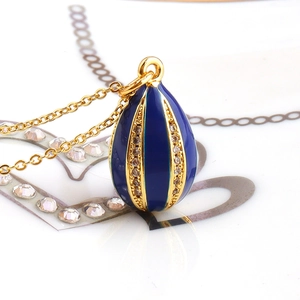 Macro shot of blue enamel egg pendant necklace with gold chain and zircon inlay details