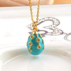 Macro view of blue enamel egg pendant with gold geometric diamond-set patterns