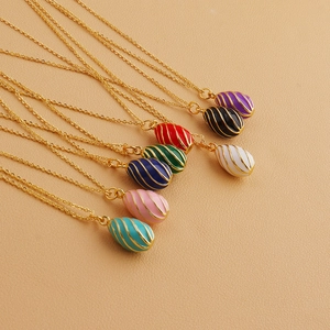 Detail of 18k gold plated enamel egg pendants in eight colors on a beige leather texture