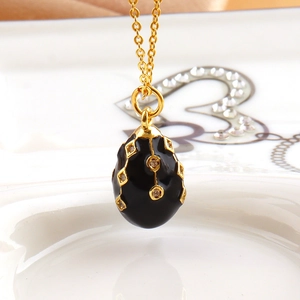 Macro view of a black enamel egg pendant with gold geometric lines and crystals