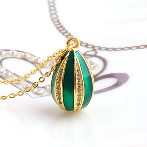 Macro shot of gold-plated egg pendant with green enamel and zircon inlay on a fine chain