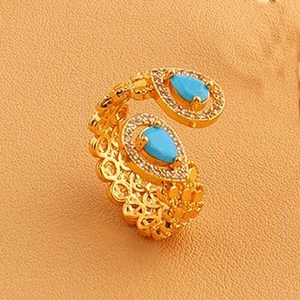 Détail macro de bague dorée avec turquoise en poire et texture tissée ajourée