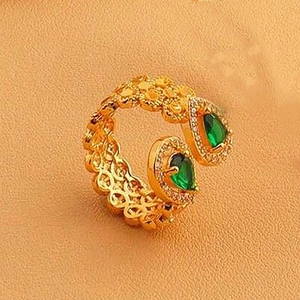 Vue détaillée d'une bague dorée ajourée avec des pierres d'émeraude verte en poire