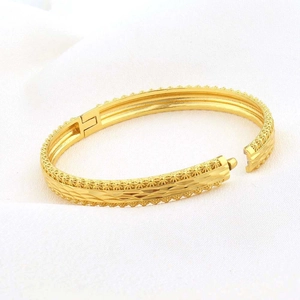 Dettaglio della trama floreale e della chiusura a scatto sul bracciale placcato oro