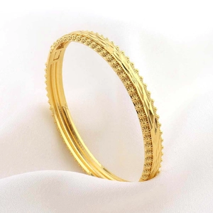 Vista macro del bracciale placcato oro con bordi a girasole e trama a onde