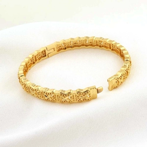 Macro-opname van vergulde armband met holle bloempatronen en een veilige sluiting