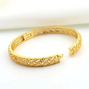 Dettaglio macro del bracciale placcato oro 24K con intricati motivi geometrici traforati