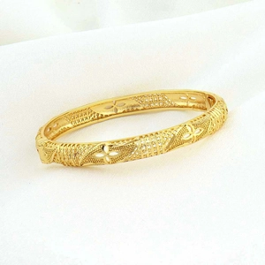 Dettaglio di un bracciale placcato oro con intricati intagli geometrici e floreali