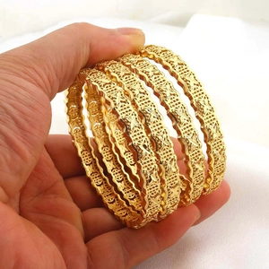 Detailopname van 24K vergulde armbanden met ingewikkelde holle bloemengravures