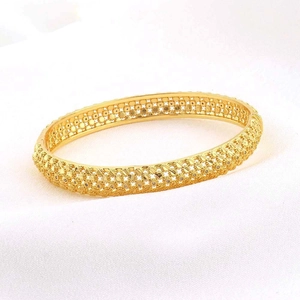 Macro-opname van 24K vergulde florale filigraanpatronen op een holle open armband goud