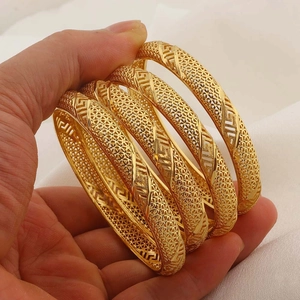 Detailopname van 4 goudkleurige armbanden met ingewikkelde Griekse sleutelpatronen