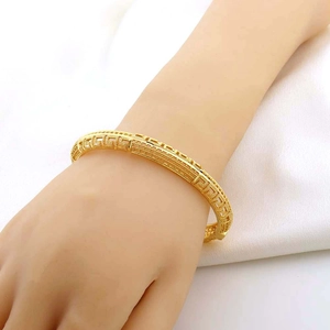 Dettaglio del bracciale traforato placcato oro 24K con motivo a greca classica sul polso