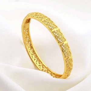 Bracciale rigido placcato oro 24K con filigrana traforata su sfondo di seta bianca