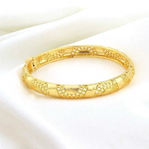 Detailopname van de vergulde armband met filigraanpatroon en handige scharniersluiting