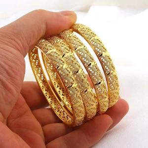 Dettaglio di quattro bracciali placcati oro 24K con intricati motivi incisi a traforo