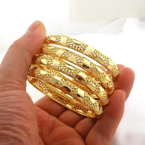 Detail van 4-delige goudkleurige U-vormige armbanden met verfijnde opengewerkte bloemmotieven