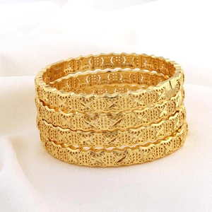Detail van vier 24K vergulde armbanden met bloemmotieven en een gegraveerde textuur