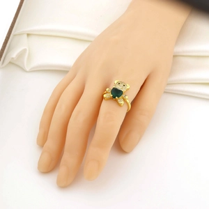 Détail d'une bague ours avec pierre en cœur vert et zircons blancs portée à la main