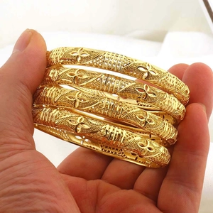 Dettaglio di quattro bracciali rigidi placcati oro 18k con incisioni floreali vintage