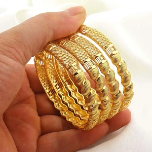 Gedetailleerde macro-opname van vier 18K vergulde armbanden met gekartelde en gegolfde patronen