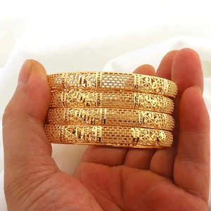 Detail von vier 24K vergoldeten Armreifen mit aufwendigen geometrischen Gravuren