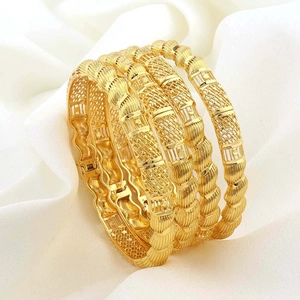 Detailopname van vier 18K vergulde holle gedraaide armbanden op witte zachte stof