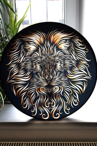 Detailed view of shamanic lion drum featuring golden totem design on a bright windowsill