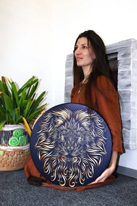 Detail of female hand holding shaman drum featuring a golden lion totem art design